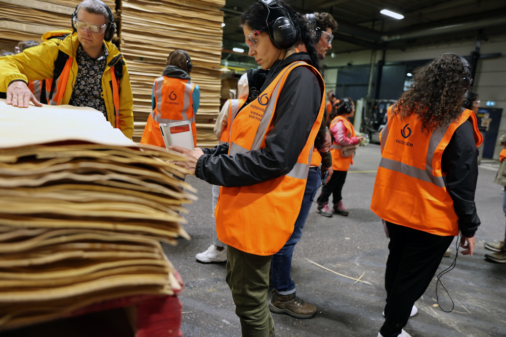 Personer tittar på plywood i industrilokal. Foto.