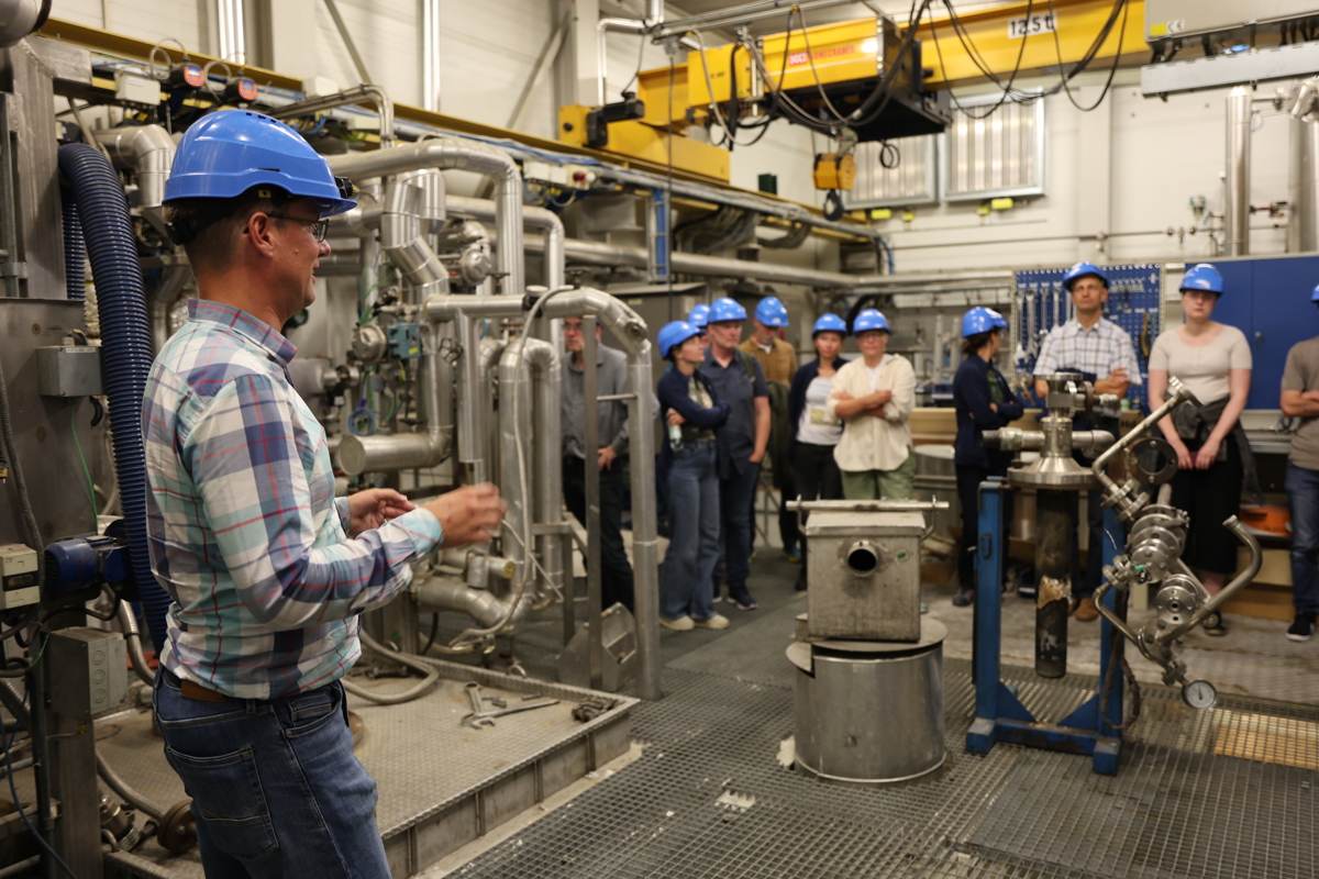 Man in blue security helmet guiding group in industrial plant. Photo.