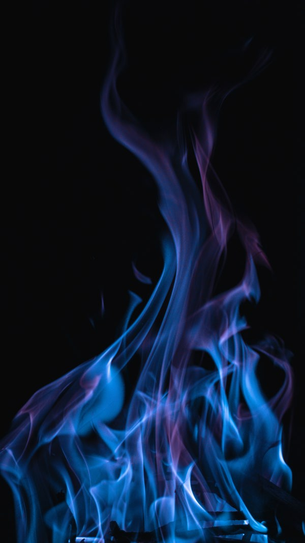 Fire with blue flames against dark background. Photo.
